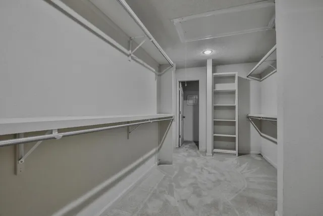 a view of walk in closet with empty racks