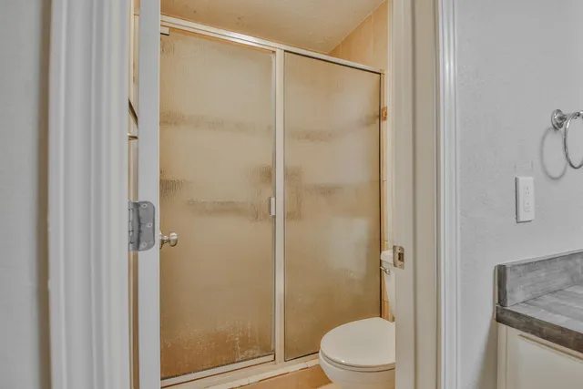 a bathroom with a granite countertop sink toilet and shower