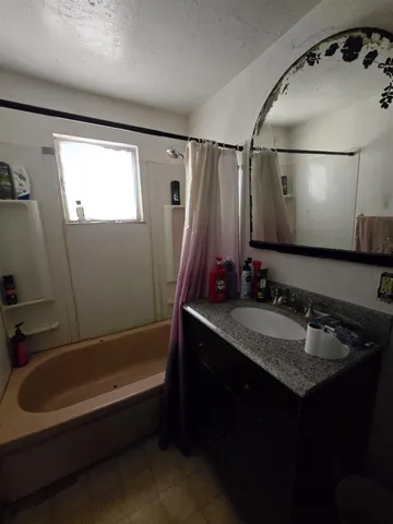 a bathroom with a granite countertop sink a mirror and a bathtub