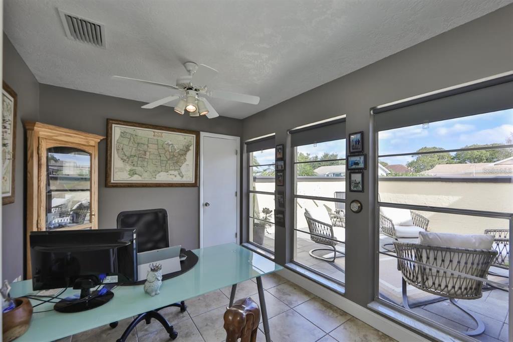 1820 El Rancho Drive Sun City Center, FL 33573 - Photo 46 of 70 a workspace with wooden floor a ceiling fan and a floor to ceiling window