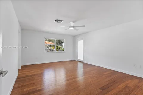 an empty room with wooden floor chandelier fan and windows