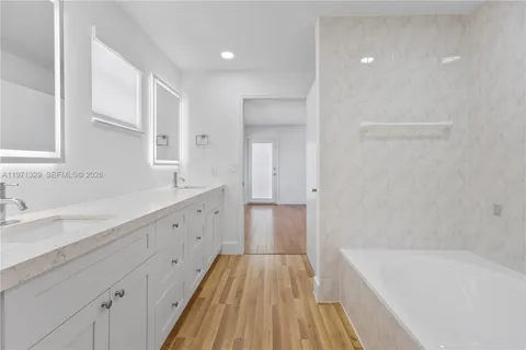 a spacious bathroom with a tub sink and mirror