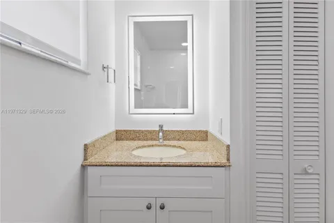 a bathroom with a granite countertop sink and a mirror
