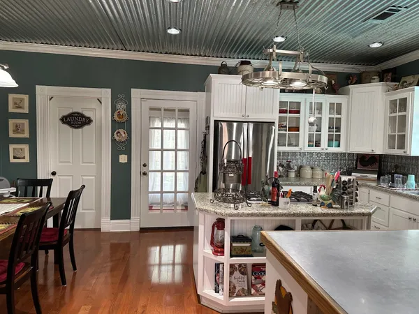 a kitchen with stainless steel appliances kitchen island granite countertop a table chairs in it and wooden floors