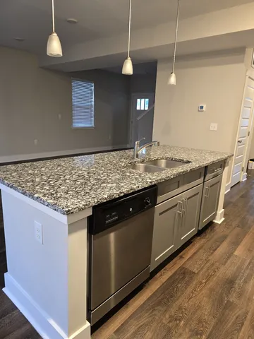 a kitchen with stainless steel appliances granite countertop wooden cabinets and a wooden floor
