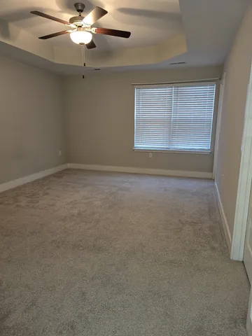 en empty room with windows and chandelier fan