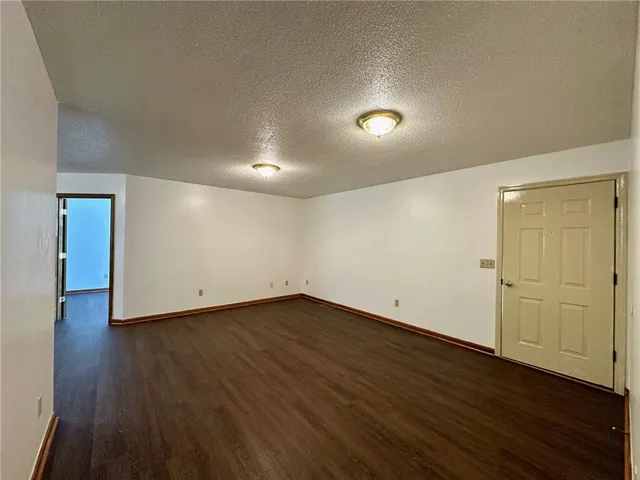 a view of an empty room with wooden floor and closet