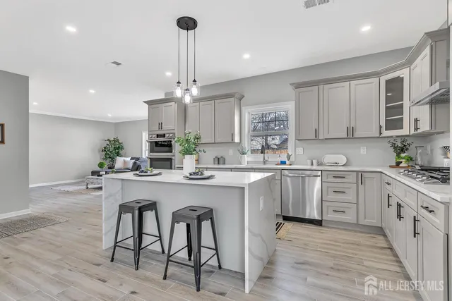 a kitchen with white cabinets stainless steel appliances and chairs