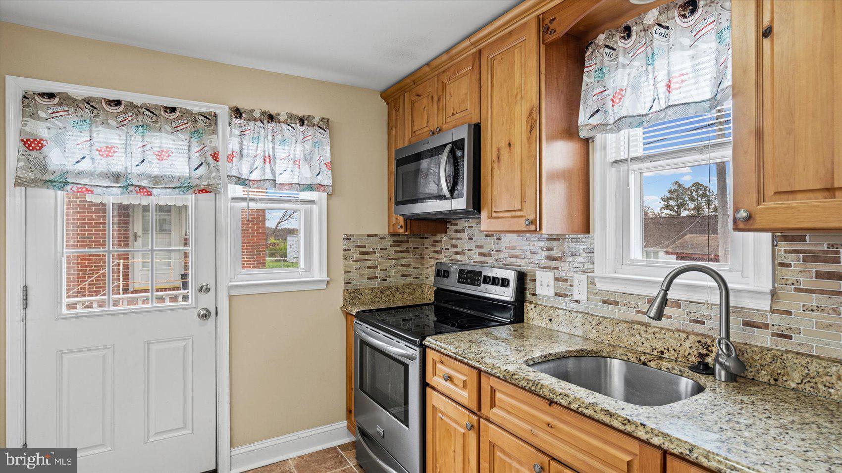 1821 Weyburn Road Baltimore, MD 21237 - Photo 12 of 45 a kitchen with stainless steel appliances granite countertop a sink and a refrigerator