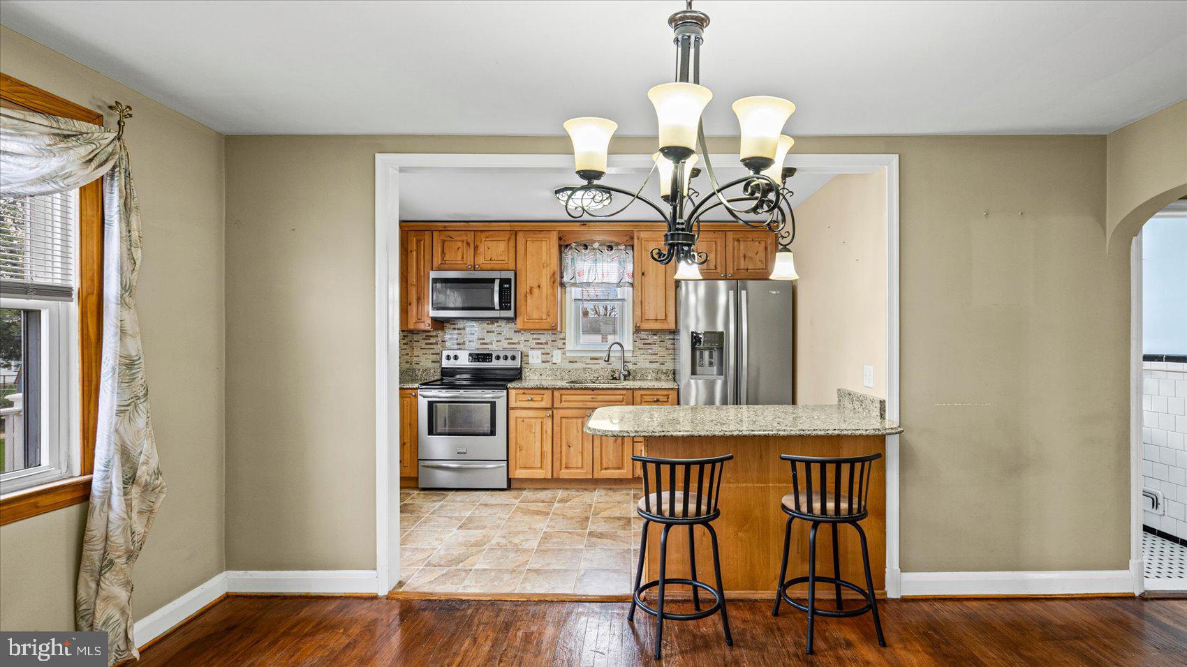 1821 Weyburn Road Baltimore, MD 21237 - Photo 9 of 45 a kitchen with stainless steel appliances granite countertop a kitchen island hardwood floor sink stove dining table and chairs