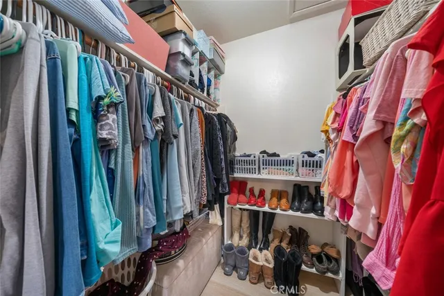a view of walk in closet with clothes and shoes