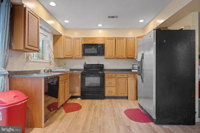 a kitchen with stainless steel appliances kitchen island granite countertop a refrigerator a sink dishwasher and a stove with wooden floor