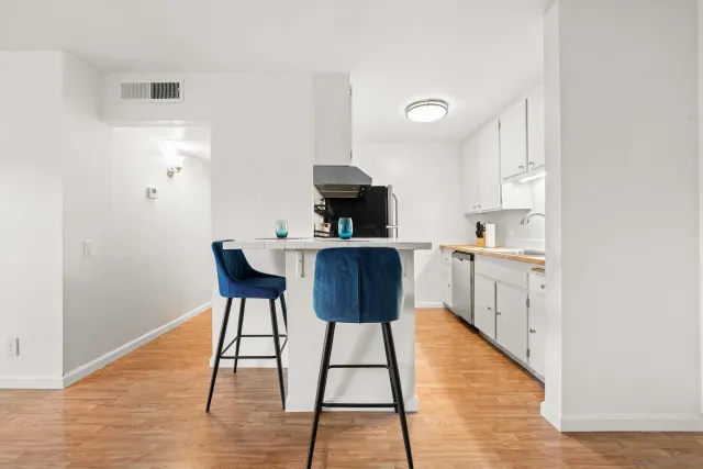 a kitchen with stainless steel appliances a dining table chairs and a refrigerator