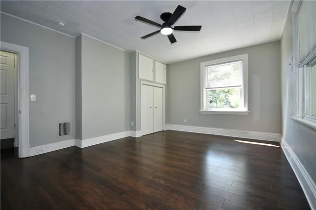 a view of an empty room with wooden floor and a window
