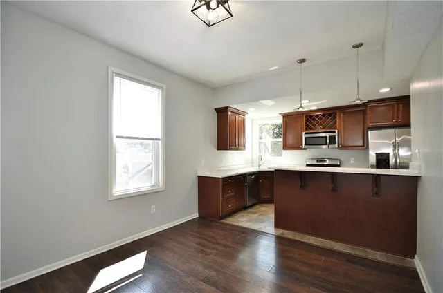 a kitchen with stainless steel appliances granite countertop a stove top oven a sink dishwasher and a microwave oven on the wooden floor