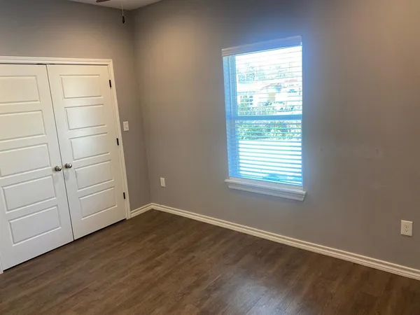 an empty room with wooden floor cabinet and windows