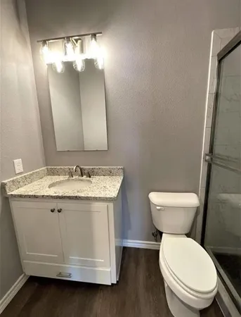 a bathroom with a granite countertop toilet sink and mirror