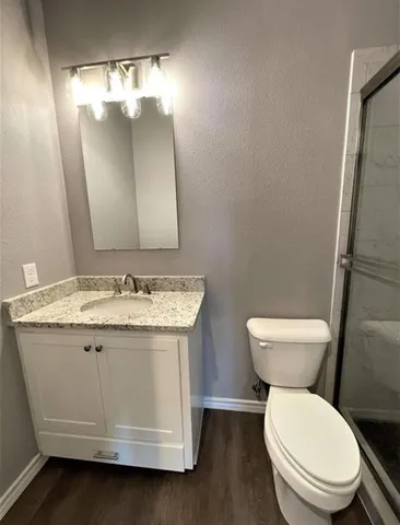 a bathroom with a granite countertop toilet sink and mirror
