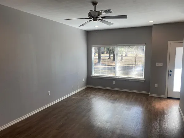 a view of an empty room with wooden floor and a window