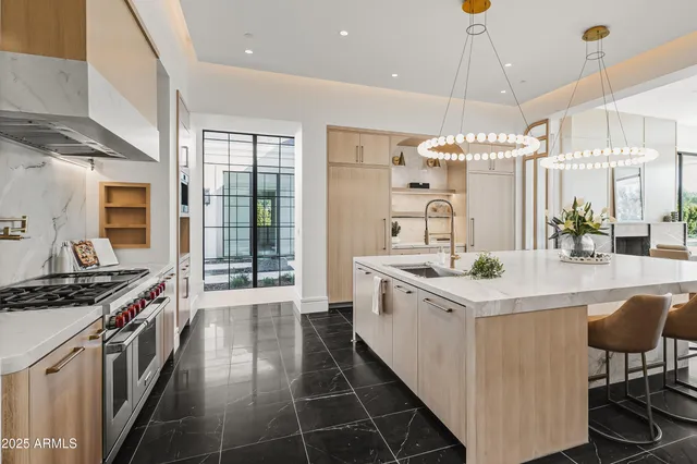 a kitchen with stainless steel appliances a stove a sink a refrigerator and chairs