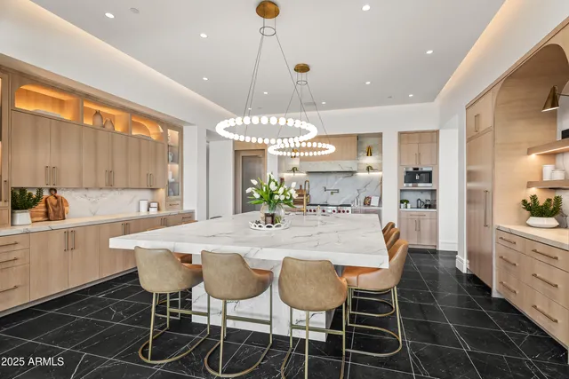 a dining table with a chandelier and kitchen view