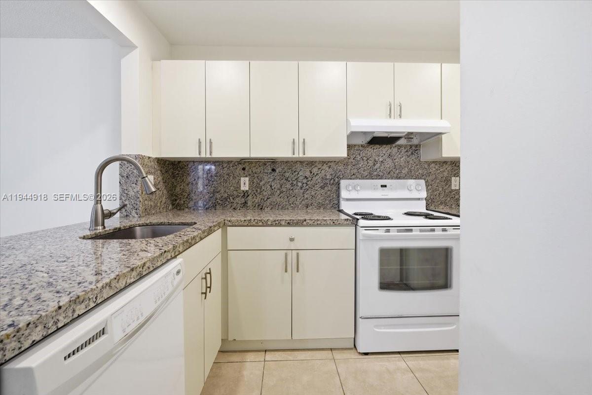 14861 Southwest 104th Street, Unit 2813 Miami, FL 33196 - Photo 9 of 21 a kitchen with granite countertop white cabinets and white appliances