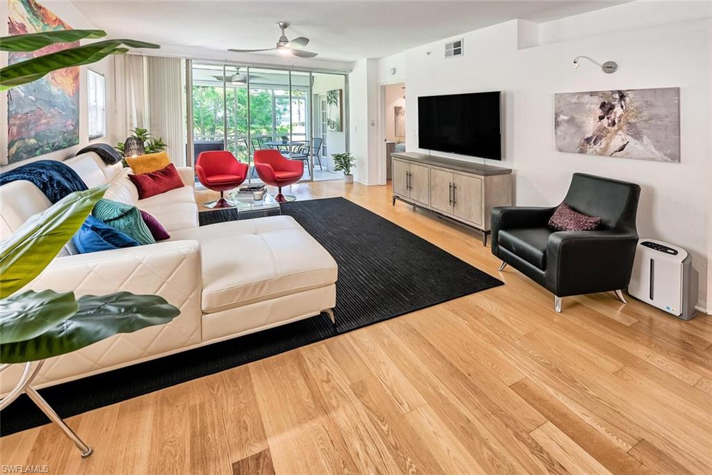 6910 Satinleaf Road North, Unit 101 Naples, FL 34109 - Photo 6 of 30 Living room featuring light hardwood / wood-style floors, ceiling fan, and a wall of windows