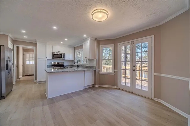 a large kitchen with stainless steel appliances granite countertop a refrigerator a stove a sink and a large window