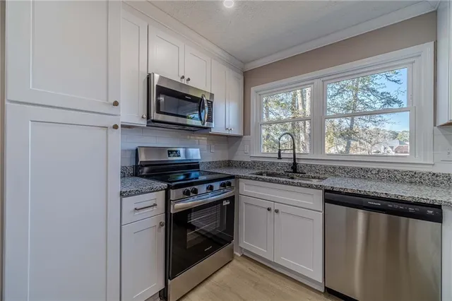 a kitchen with stainless steel appliances granite countertop white cabinets granite counter tops and a window