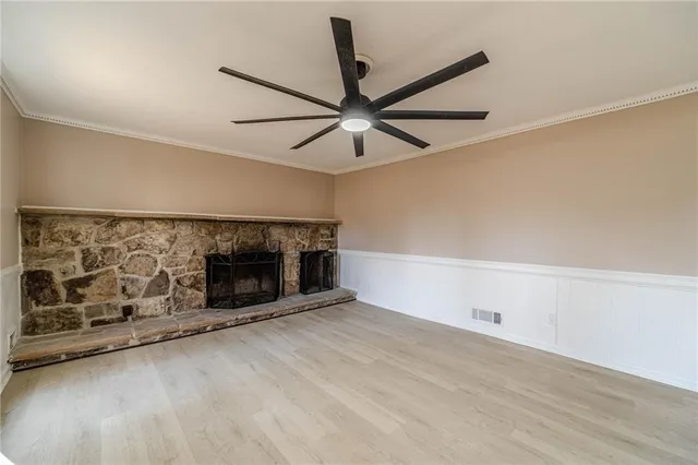 a living room with stainless steel appliances wooden floor and a ceiling fan