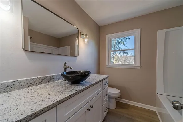 a bathroom with a granite countertop sink a toilet and mirror