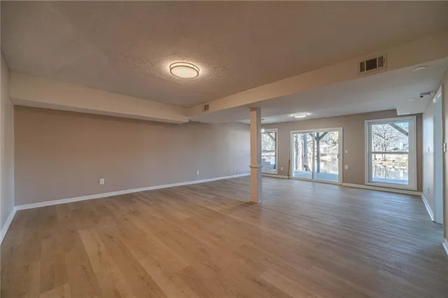 a view of an empty room with window and wooden floor
