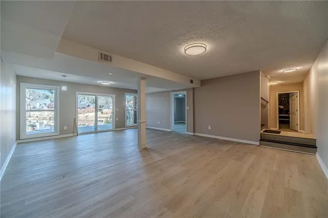 a view of an empty room with window and wooden floor