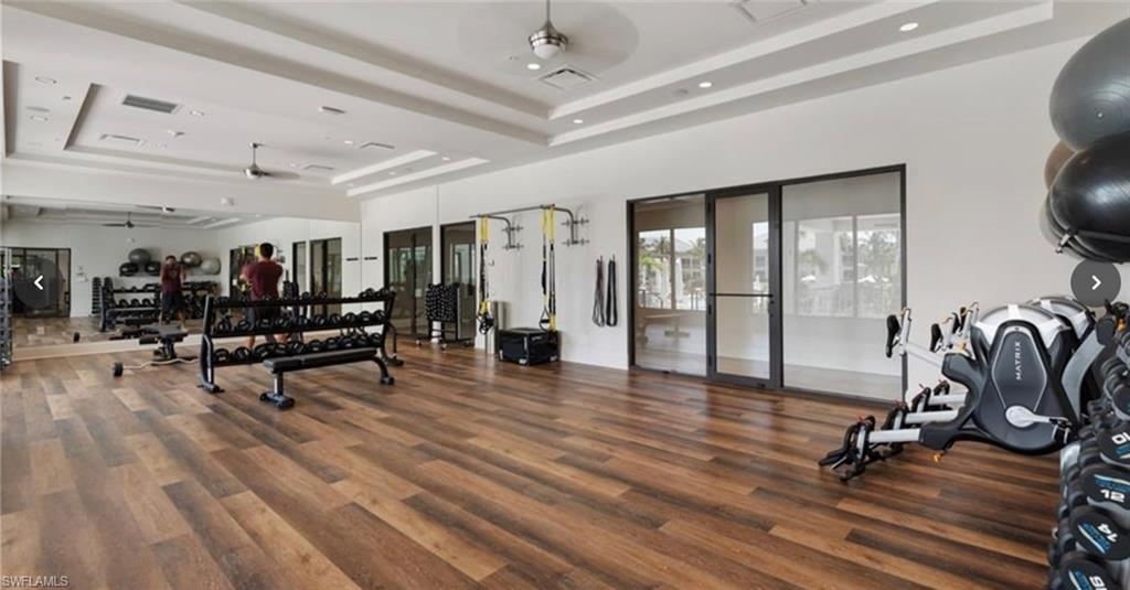 285 Grande Way, Unit 705 Naples, FL 34110 - Photo 35 of 44 Workout area featuring a tray ceiling, dark wood-type flooring, and ceiling fan