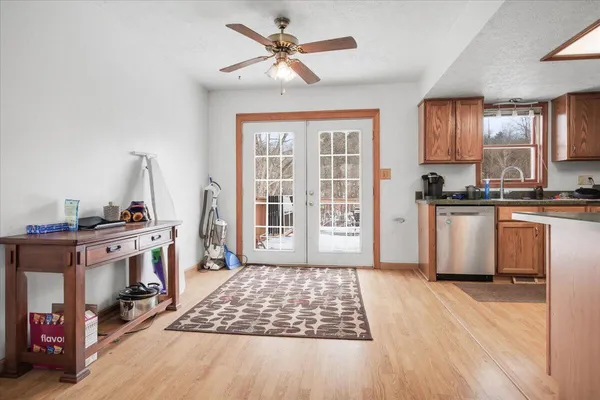 a open kitchen with stainless steel appliances granite countertop a stove a sink dishwasher and a fireplace with wooden floor