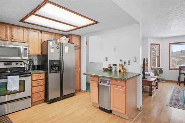 a kitchen with stainless steel appliances kitchen island granite countertop a table chairs stove refrigerator and cabinets