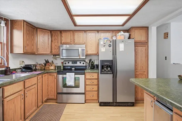 a kitchen with stainless steel appliances granite countertop a refrigerator a stove and a sink