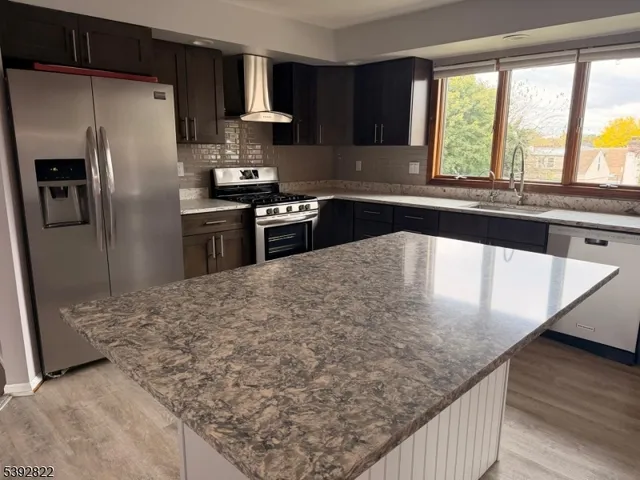 a kitchen with stainless steel appliances granite countertop a sink window and refrigerator