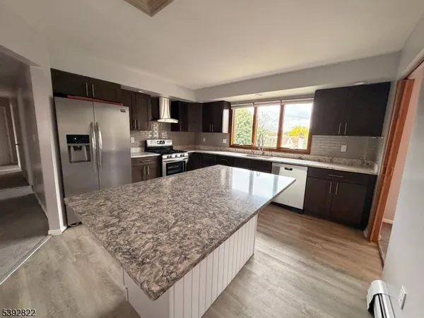 a kitchen with stainless steel appliances granite countertop a sink dishwasher stove top oven and refrigerator