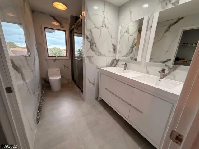a bathroom with a double vanity sink toilet and a tub