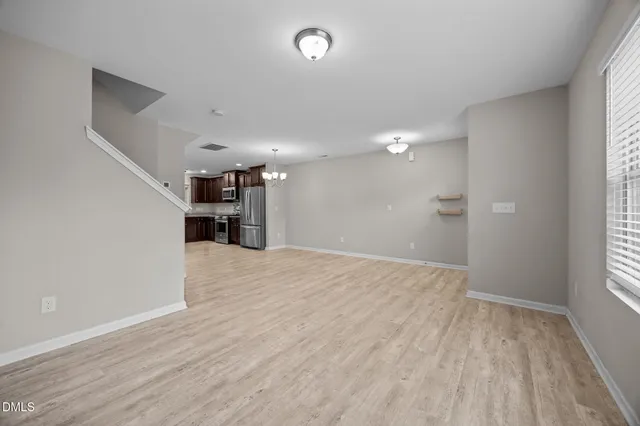 a view of empty room with wooden floor and window