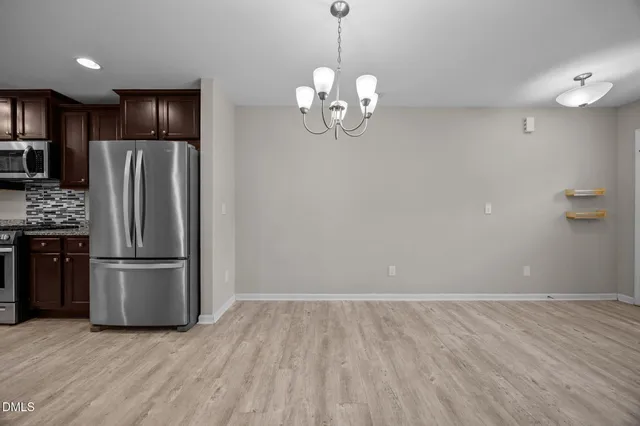 a view of a kitchen with a refrigerator a ceiling fan and a wooden floor