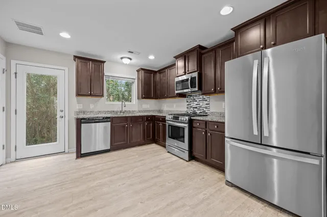 a kitchen with stainless steel appliances granite countertop a refrigerator sink and stove