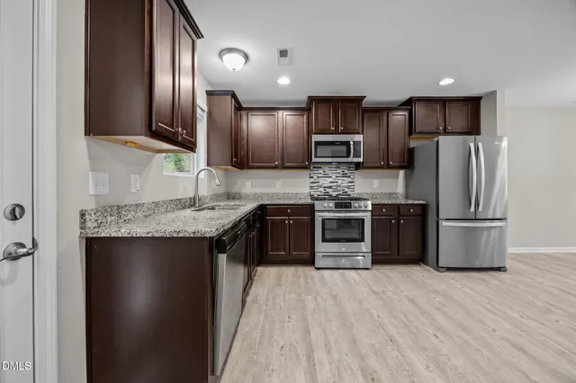 a kitchen with stainless steel appliances granite countertop a refrigerator and a stove top oven
