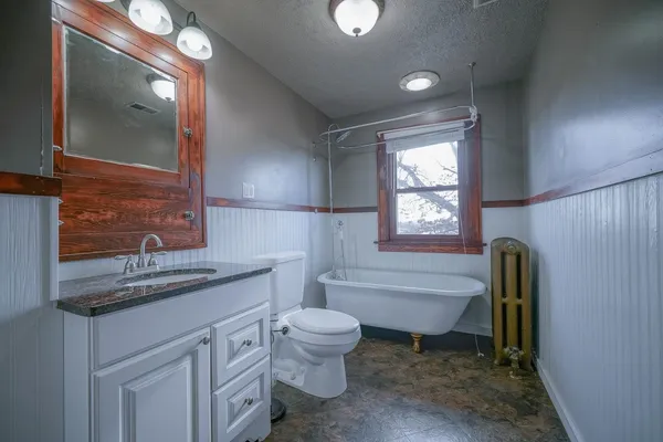 a bathroom with a granite countertop toilet a sink and a bathtub