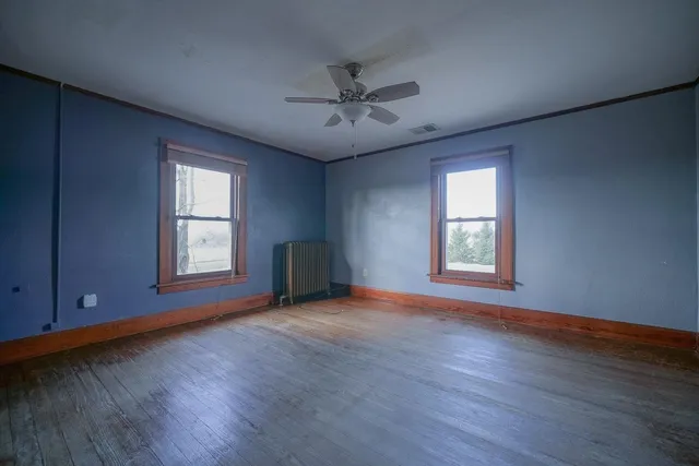 an empty room with wooden floor and windows