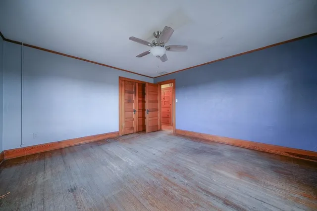 a view of an empty room with window and wooden floor