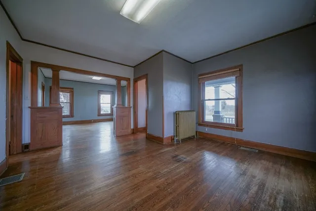 a view of an empty room with wooden floor and a window
