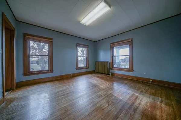a view of an empty room with wooden floor and a window