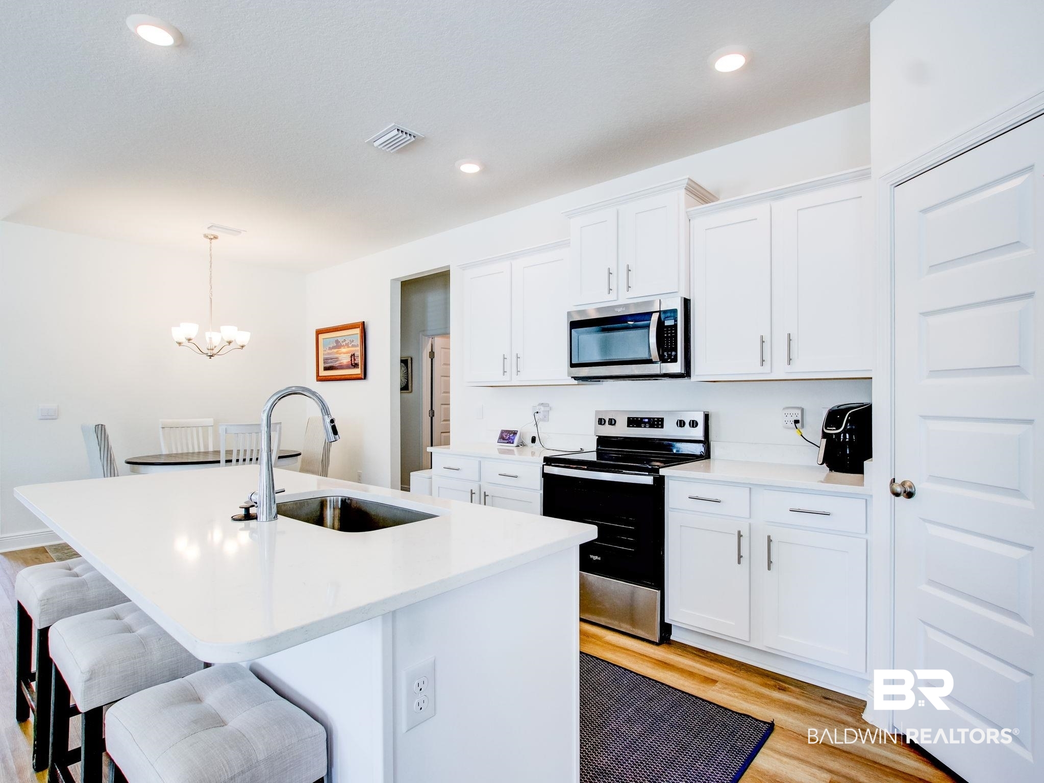 12919 Torrent Road Fairhope, AL 36532 - Photo 72 of 74 Kitchen featuring stainless steel appliances, a breakfast bar, light wood-style floors, white cabinets, and a center island with sink